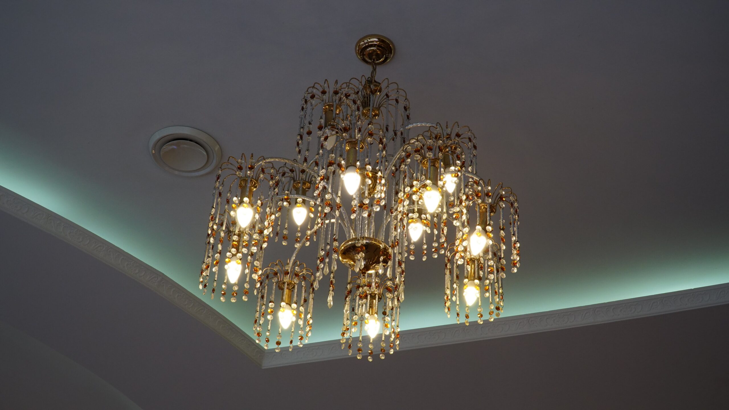Luxurious crystal chandelier on the ceiling. Bottom view. Close-up. Huge crystal gold chandelier with candles. luxurious crystal chandelier on the ceiling botto 2022 10 27 18 32 23 utc scaled